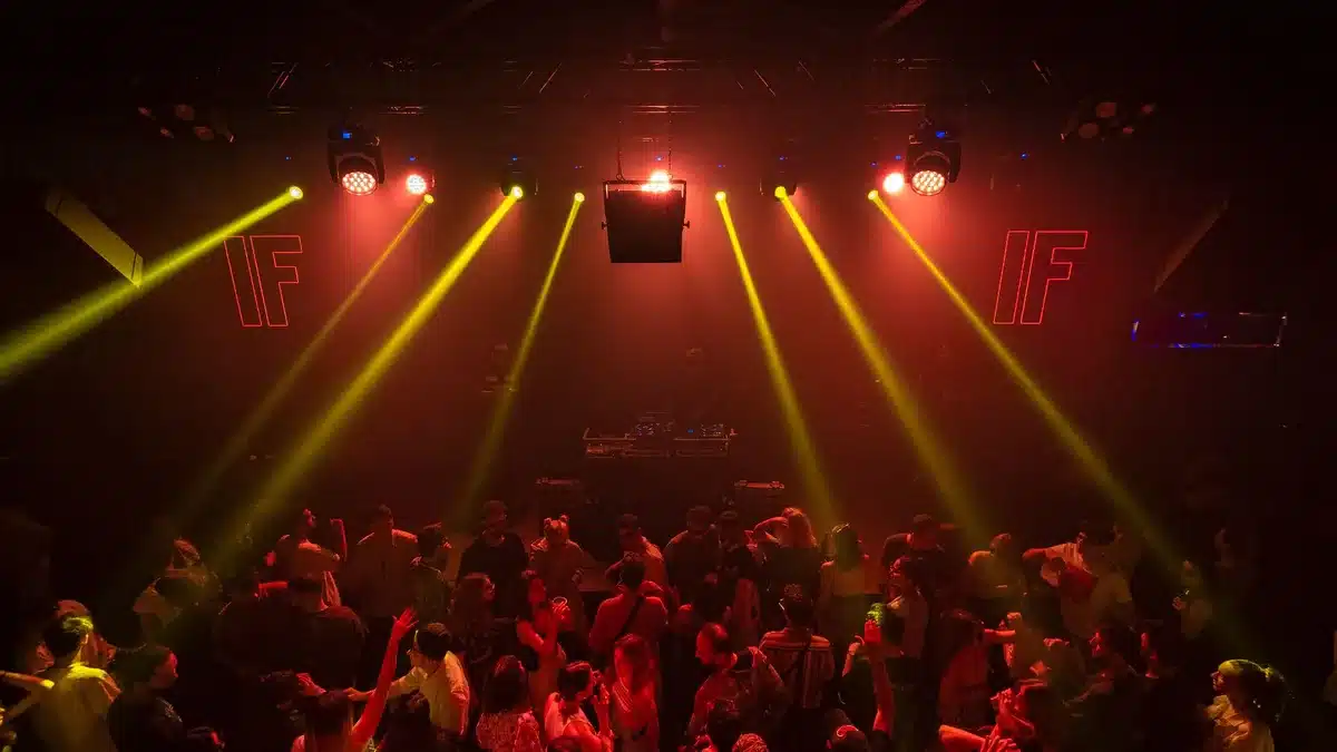 Piste de danse dans un club avec éclairage neon et architecture industrielle en arrière-plan