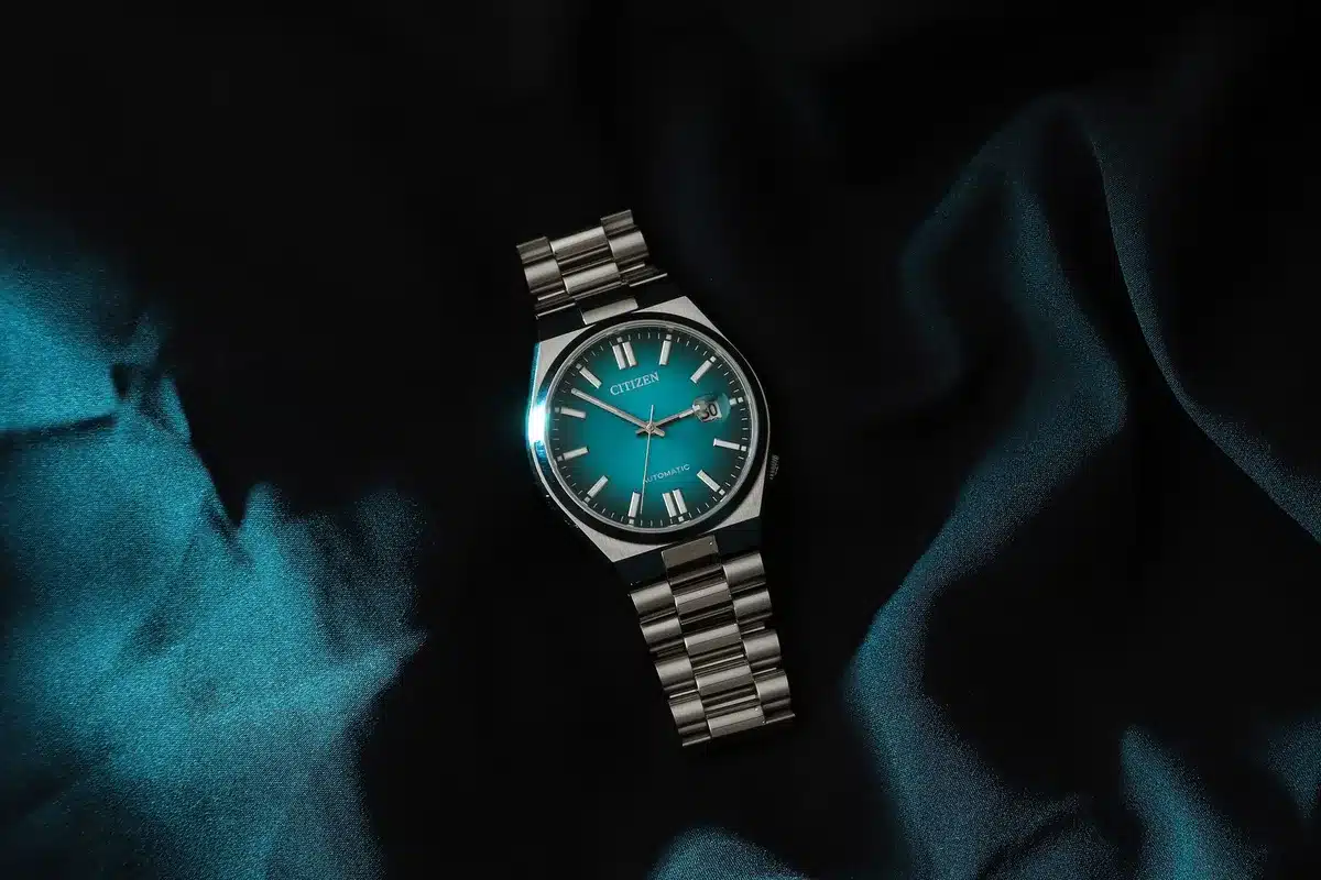 Montre avec cadran vert sauge affichant des reflets argentés subtils sous la lumière
