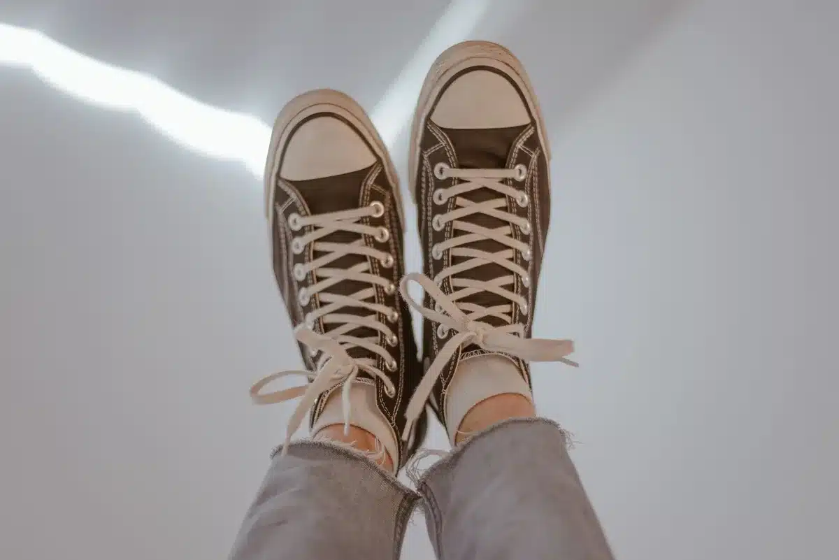 Mains anonymes laçant une paire de baskets de running vintage aux lignes épurées