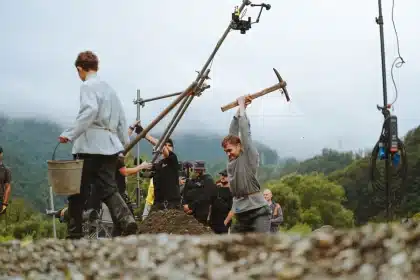 Équipe de tournage sur un plateau de cinéma en pleine préparation, avec matériel et acteurs en arrière-plan