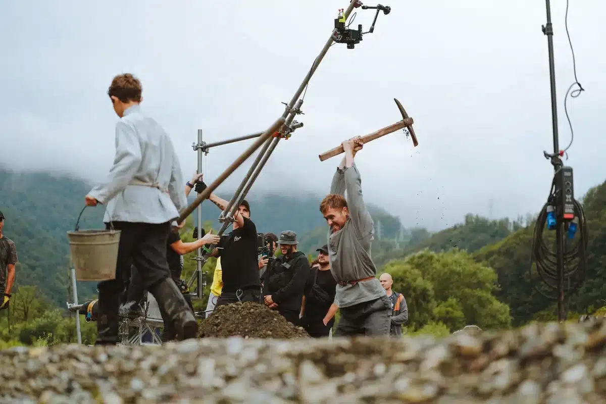 Équipe de tournage sur un plateau de cinéma en pleine préparation, avec matériel et acteurs en arrière-plan
