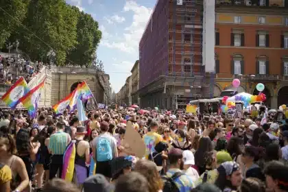 Foule de personnes avec drapeaux arc-en-ciel lors d'une marche des fiertés