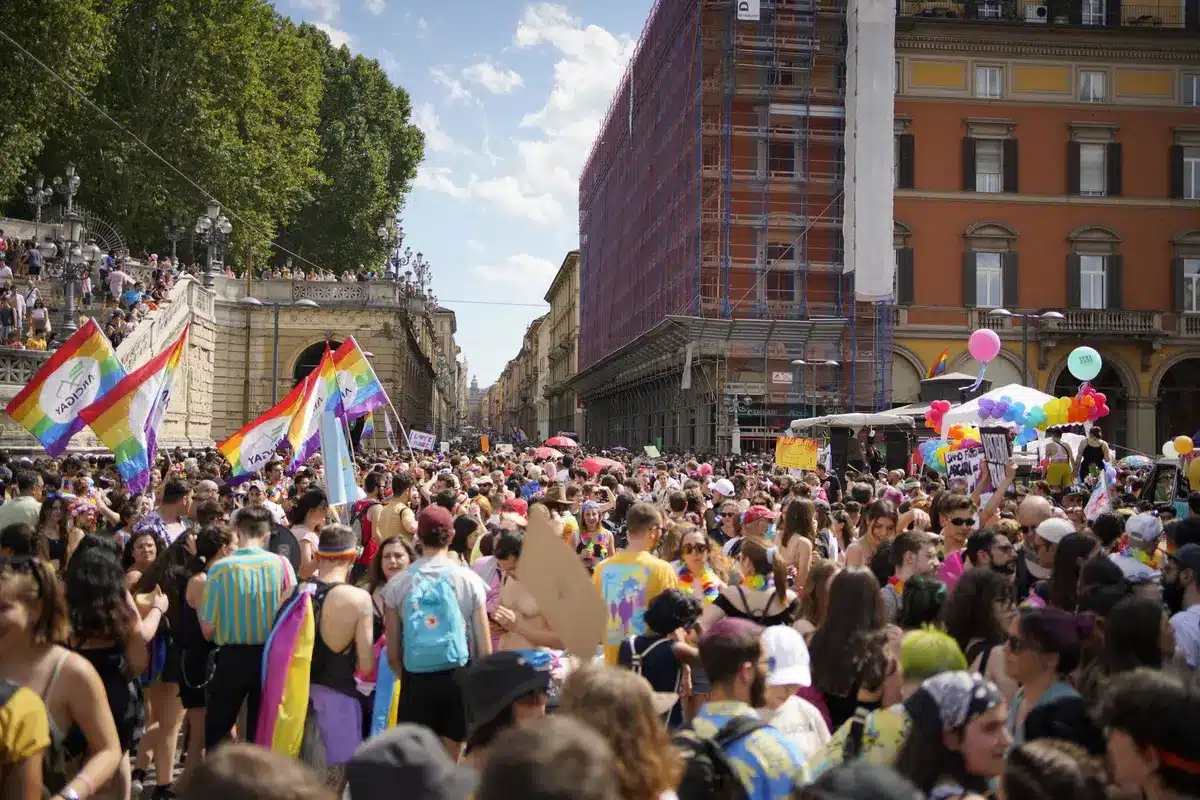 Foule de personnes avec drapeaux arc-en-ciel lors d'une marche des fiertés