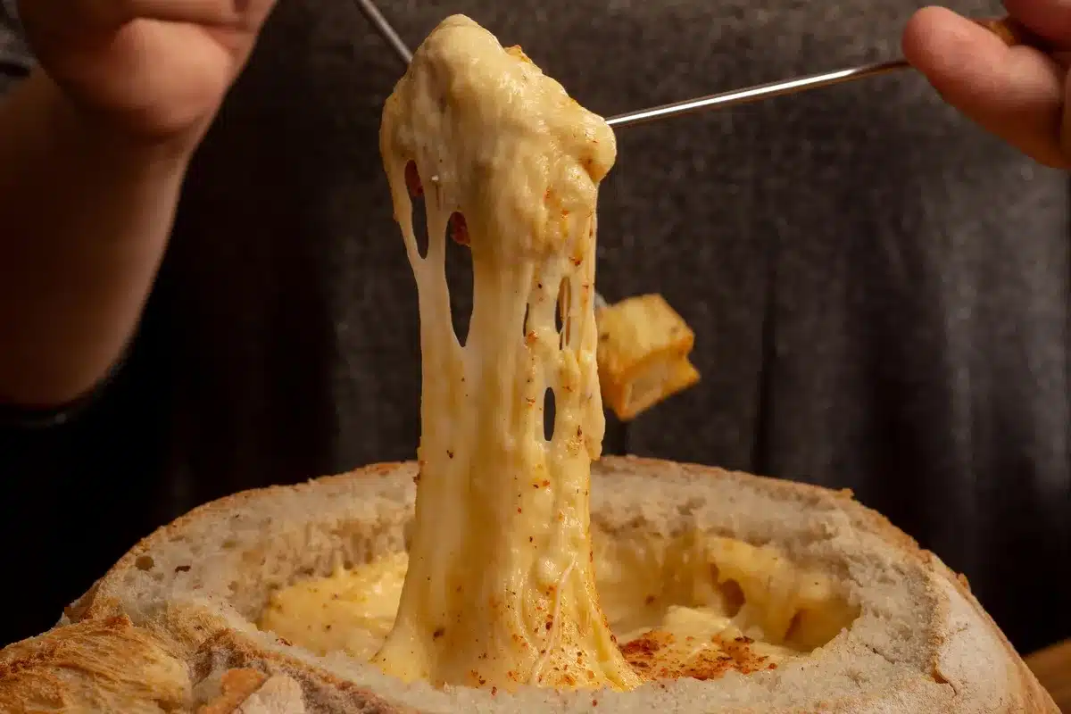 Appareil à raclette traditionnel avec demi-meule fondant, convivialité festive en montagne