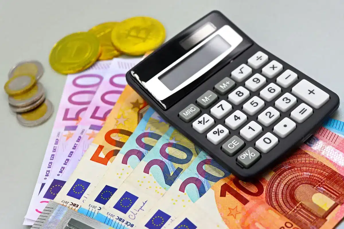 Pièces de monnaie, billets et documents financiers sur un bureau avec une calculatrice