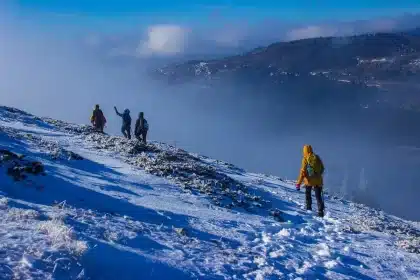 Paire de chaussures de randonnée imperméables posée sur des rochers mouillés avec un sac à dos flou