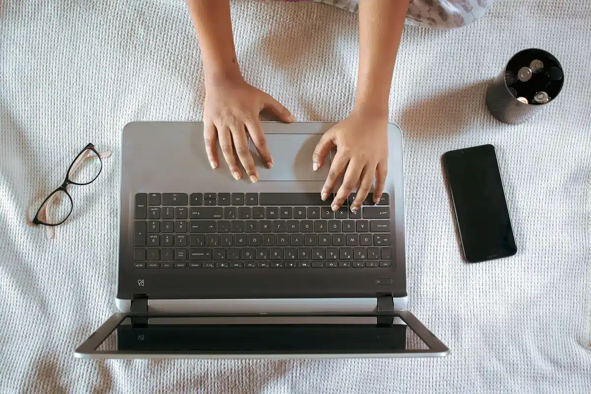 Mains au‑dessus d’un clavier et fenêtre de navigateur floue sur un écran