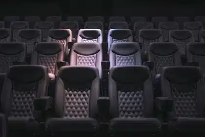 Silhouettes d'un public en salle de cinéma avec des billets et un siège vide
