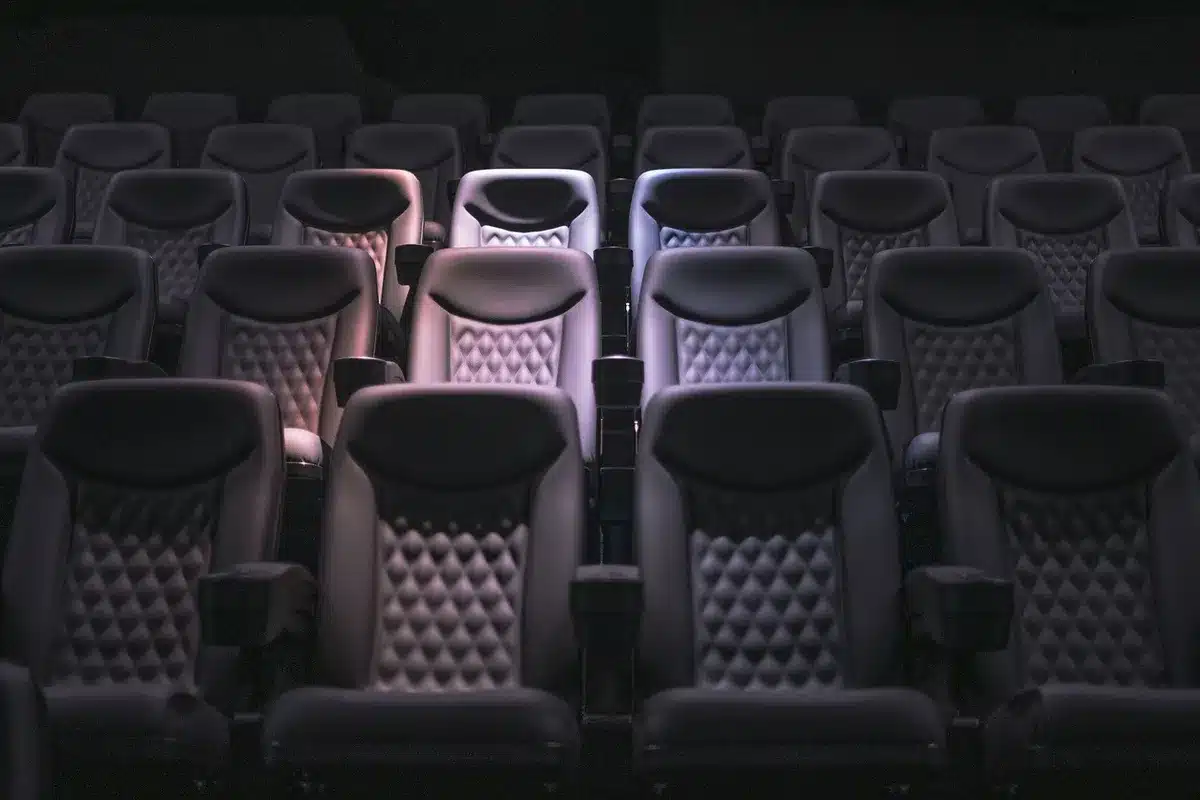 Silhouettes d'un public en salle de cinéma avec des billets et un siège vide
