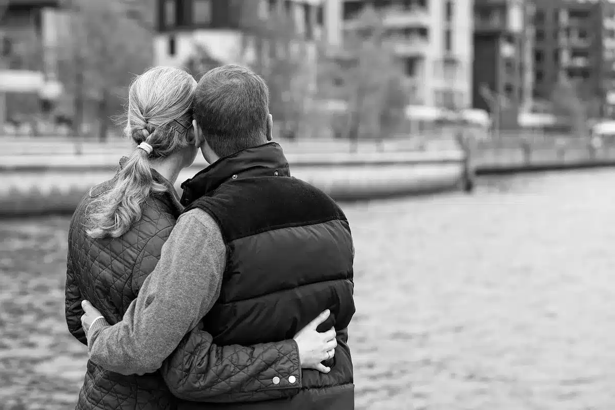 Plan serré sur un couple échangeant un regard dans une pièce éclairée, tension contenue