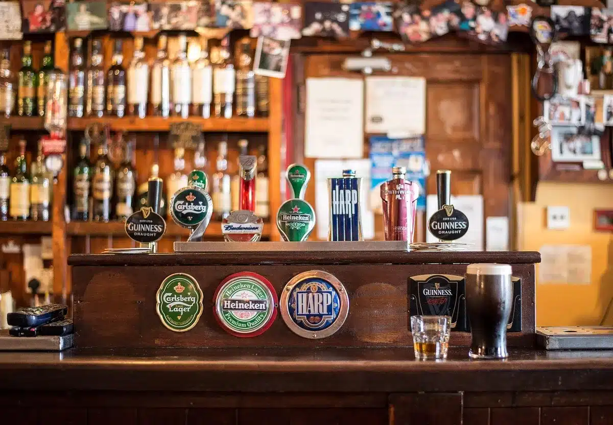 Comptoir de bar avec verres et bouteilles de boissons alcoolisées et non alcoolisées.