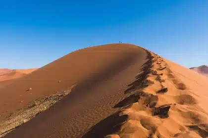 Deux silhouettes près de petites navettes ensablées au crépuscule, paysage de plaines craquelées