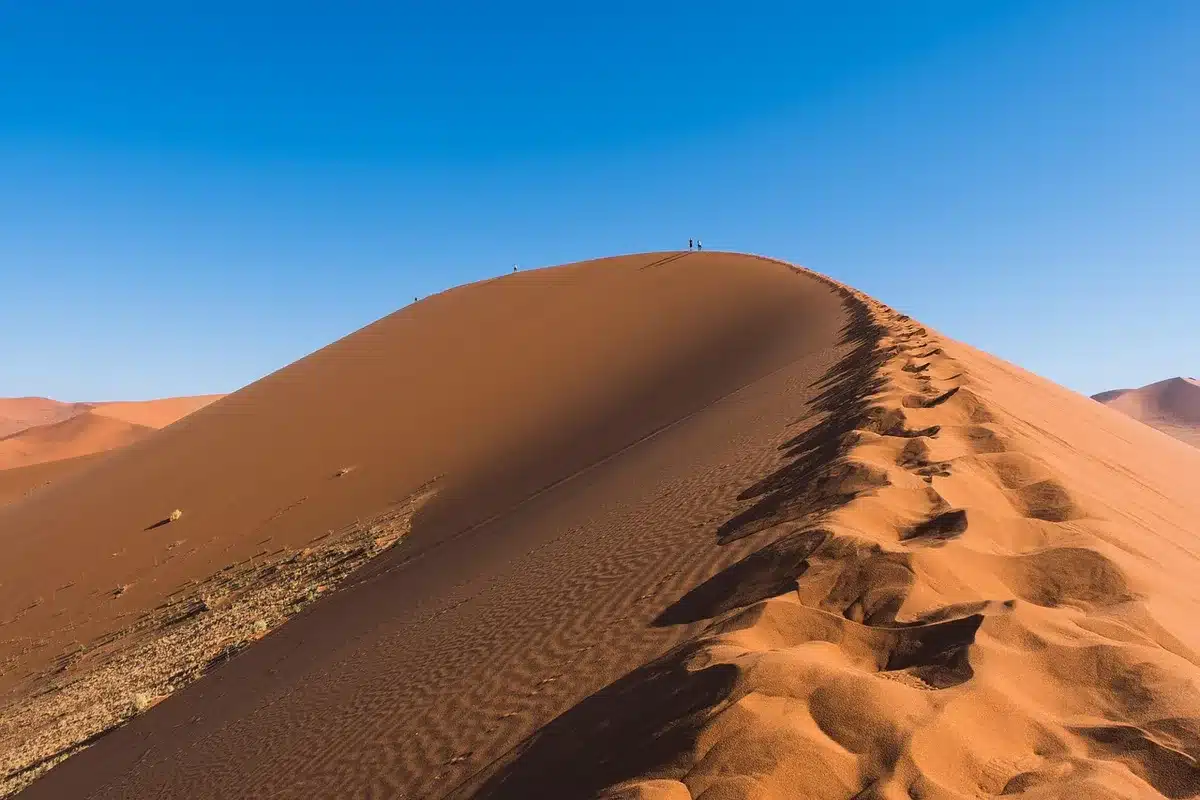 Deux silhouettes près de petites navettes ensablées au crépuscule, paysage de plaines craquelées
