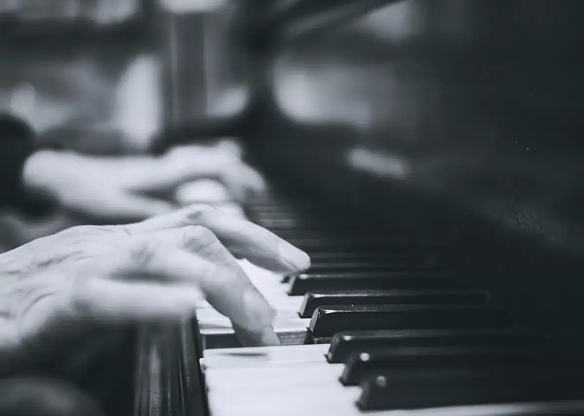 Mains anonymes réglant une table de mixage et un synthétiseur lors d'une répétition