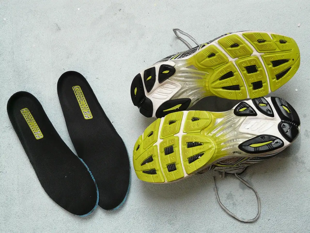 Deux boîtes de sneakers néon bleu et vert posées sur une table de studio, mains anonymes tenant les boîtes