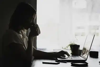 Poste de travail anonyme avec écran de code et mains prenant des notes