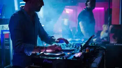 Silhouette d'une DJ derrière des platines dans un club, ambiance industrielle