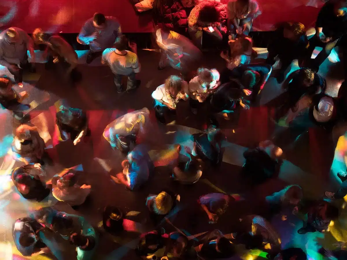 Foule sur le dancefloor baignée de lumières néon et fumée