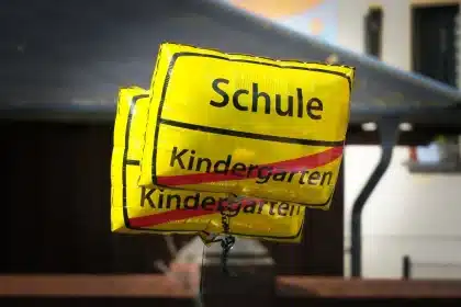 Cour d'école avec tablette sur un banc et baskets d'enfant, silhouettes d'élèves en arrière-plan