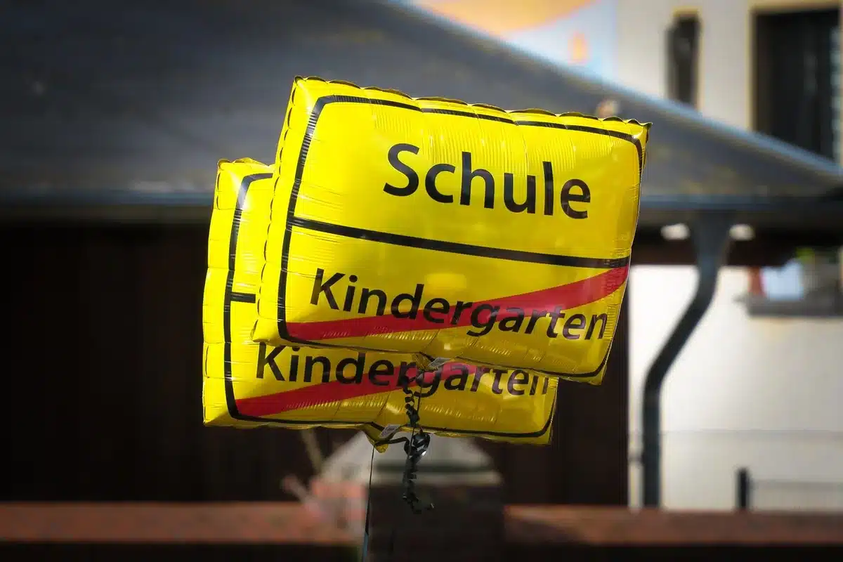 Cour d'école avec tablette sur un banc et baskets d'enfant, silhouettes d'élèves en arrière-plan