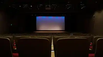 Foule anonyme dans une salle de conférence regardant un écran lumineux