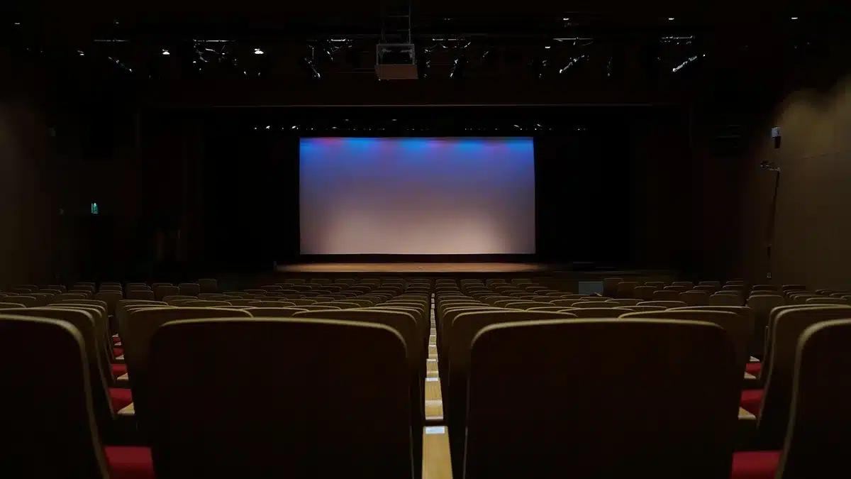 Foule anonyme dans une salle de conférence regardant un écran lumineux